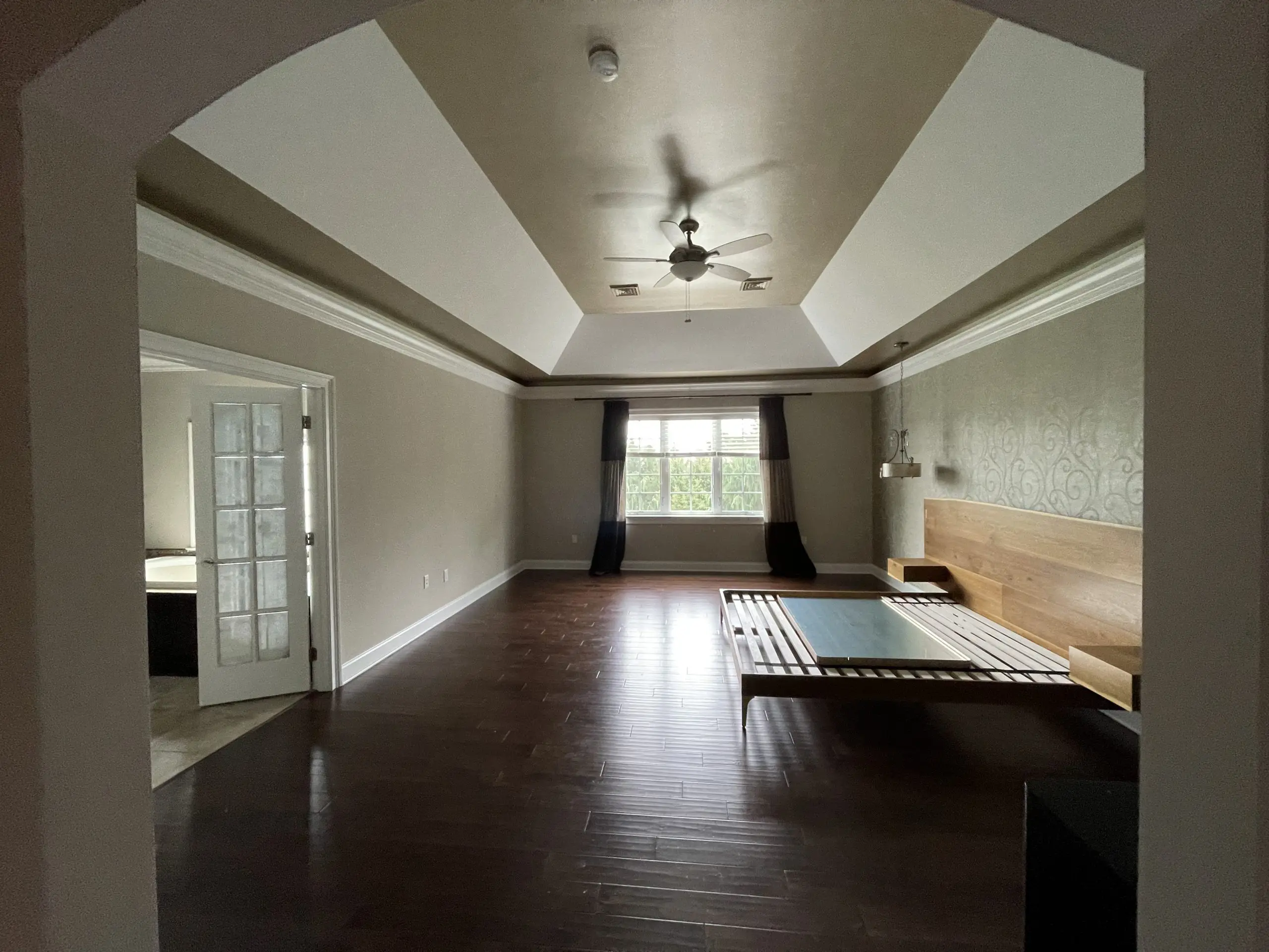 Elegant primary bedroom featuring a tray ceiling, crown molding, and hardwood floors expertly finished by professional painters in Leola, PA.
