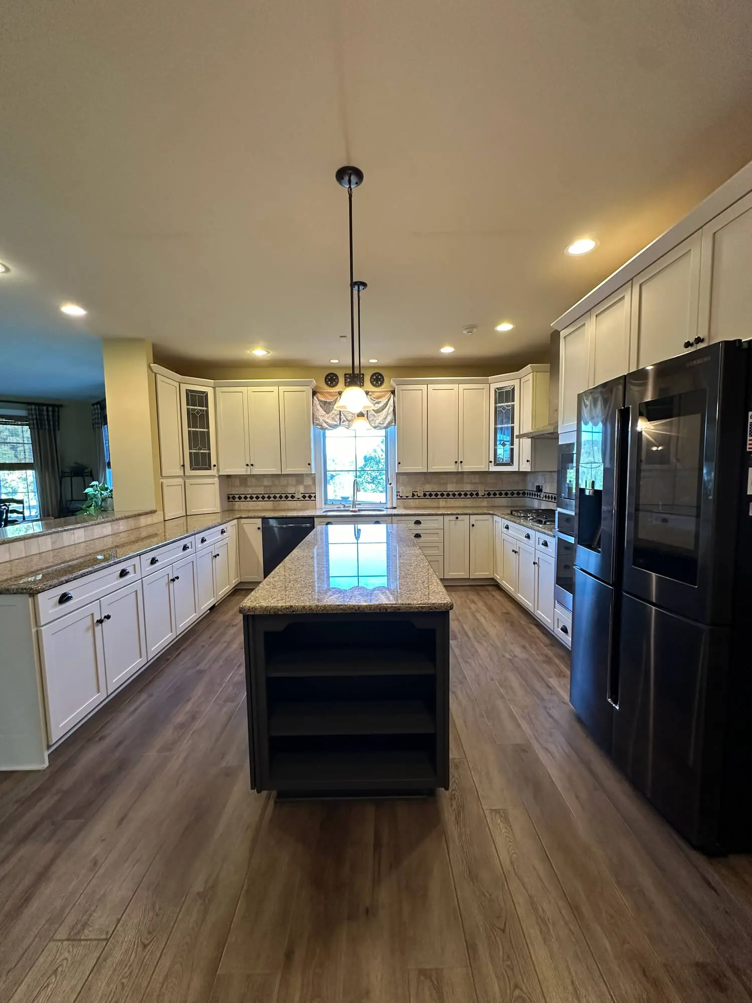 Spacious kitchen with freshly painted white cabinets, granite island, and modern black appliances, showcasing high-quality work by trusted painters in Lititz, PA