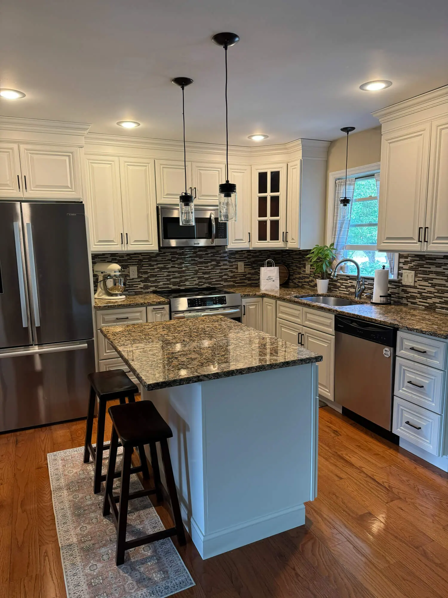 Bright white kitchen cabinet painting with granite countertops and modern backsplash, completed by professional painters in Lititz, PA for a clean and updated look
