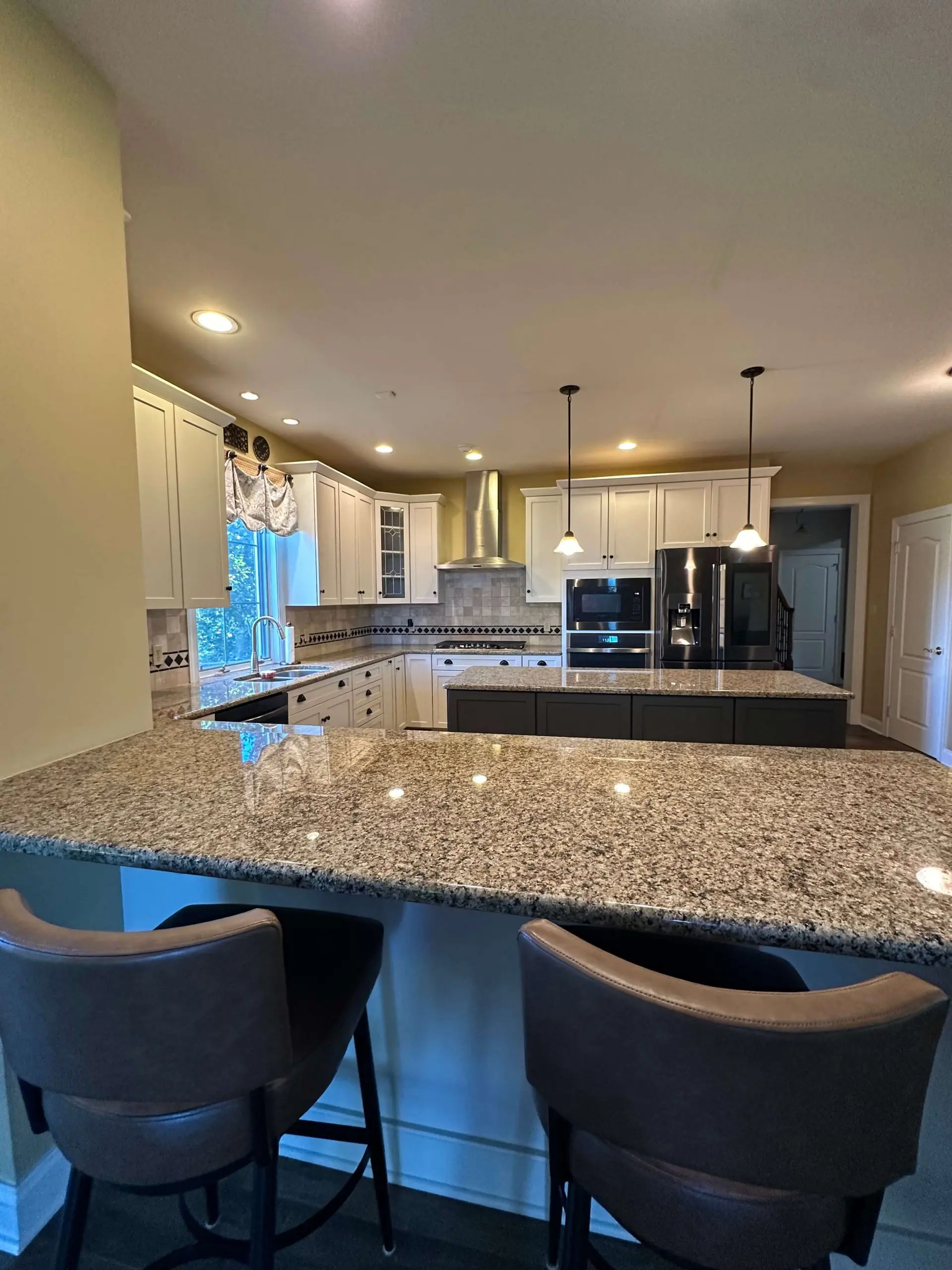 Elegant kitchen remodel showcasing granite countertops and a dark wood island by Martzall's Custom Surfaces.