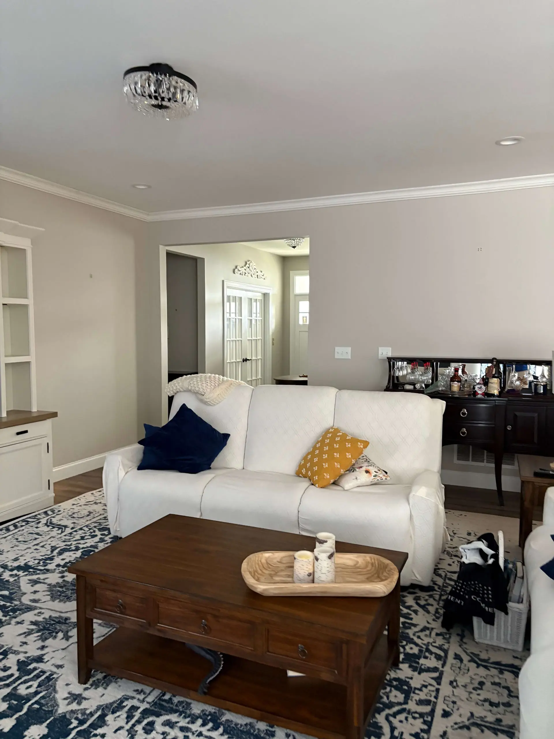 A well-lit transitional living room featuring a white sofa with navy and mustard pillows atop a blue patterned rug, showcasing expert interior finishes by Martzall's Custom Surfaces.