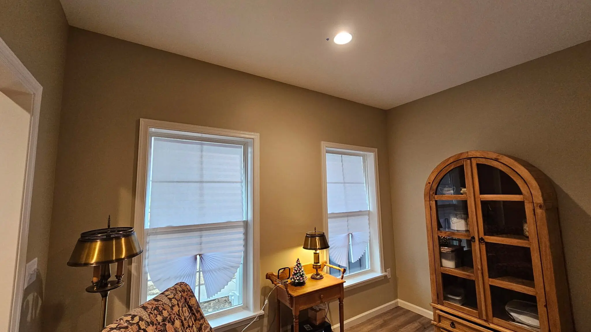 martzalls custom surface maintains this brightly lit cozy room featuring arched wooden cabinetry, warm lamps, and unique pleated window shades.