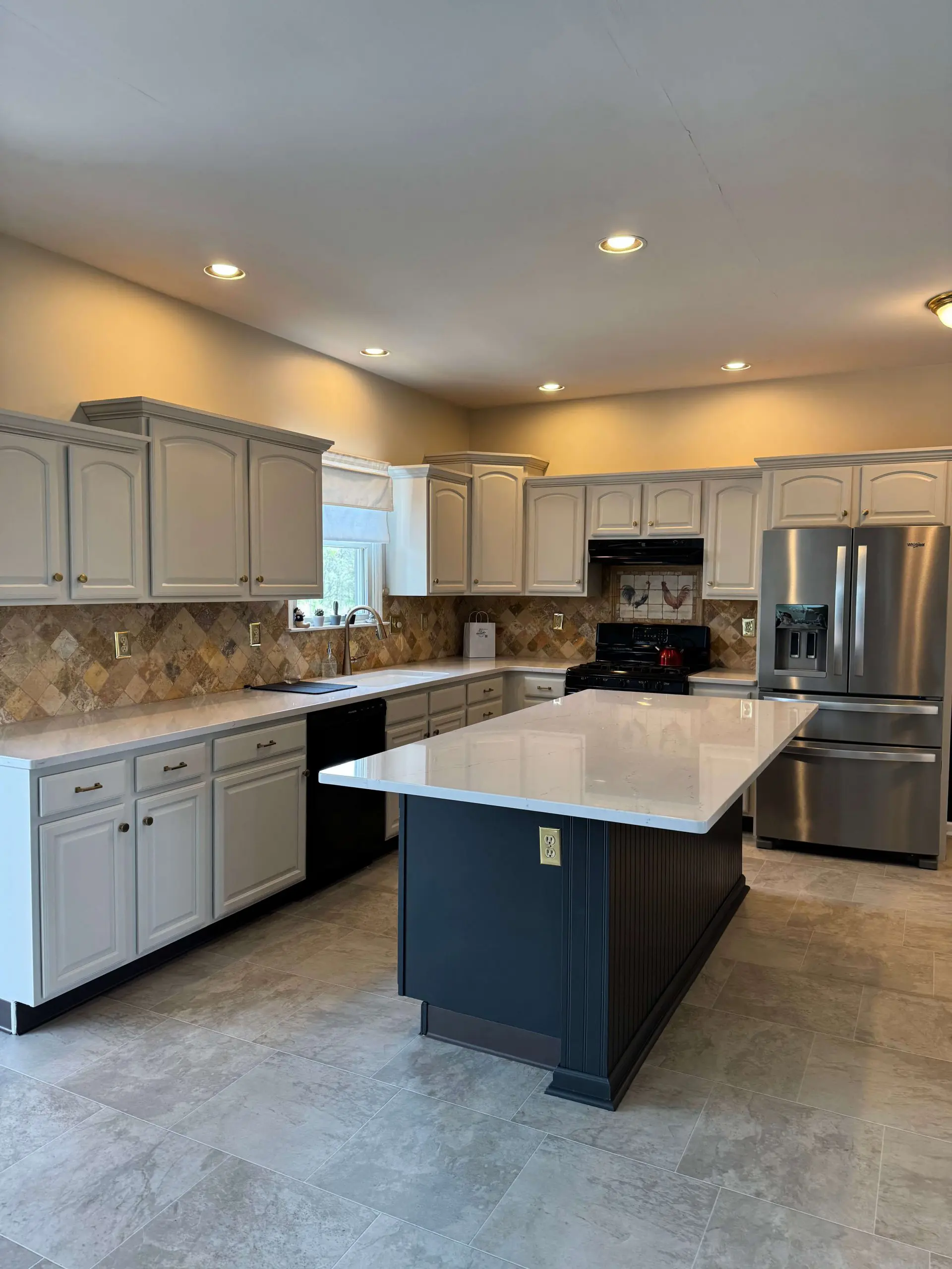 Modern kitchen renovation by Martzall's Custom Surfaces featuring white quartz countertops, a charcoal beadboard island, and arched cabinetry.