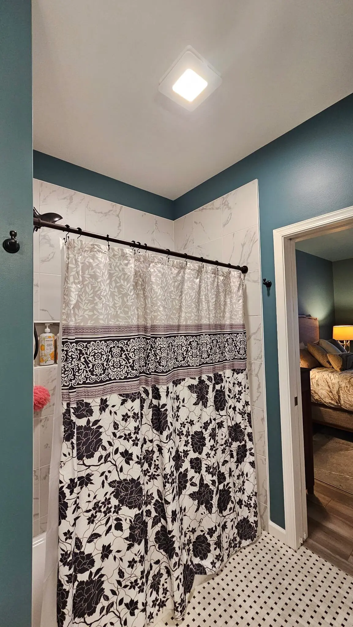 Modern bathroom showcasing a marble-tiled shower with a botanical curtain and teal walls, serviced by Pmartzalls custom surface.