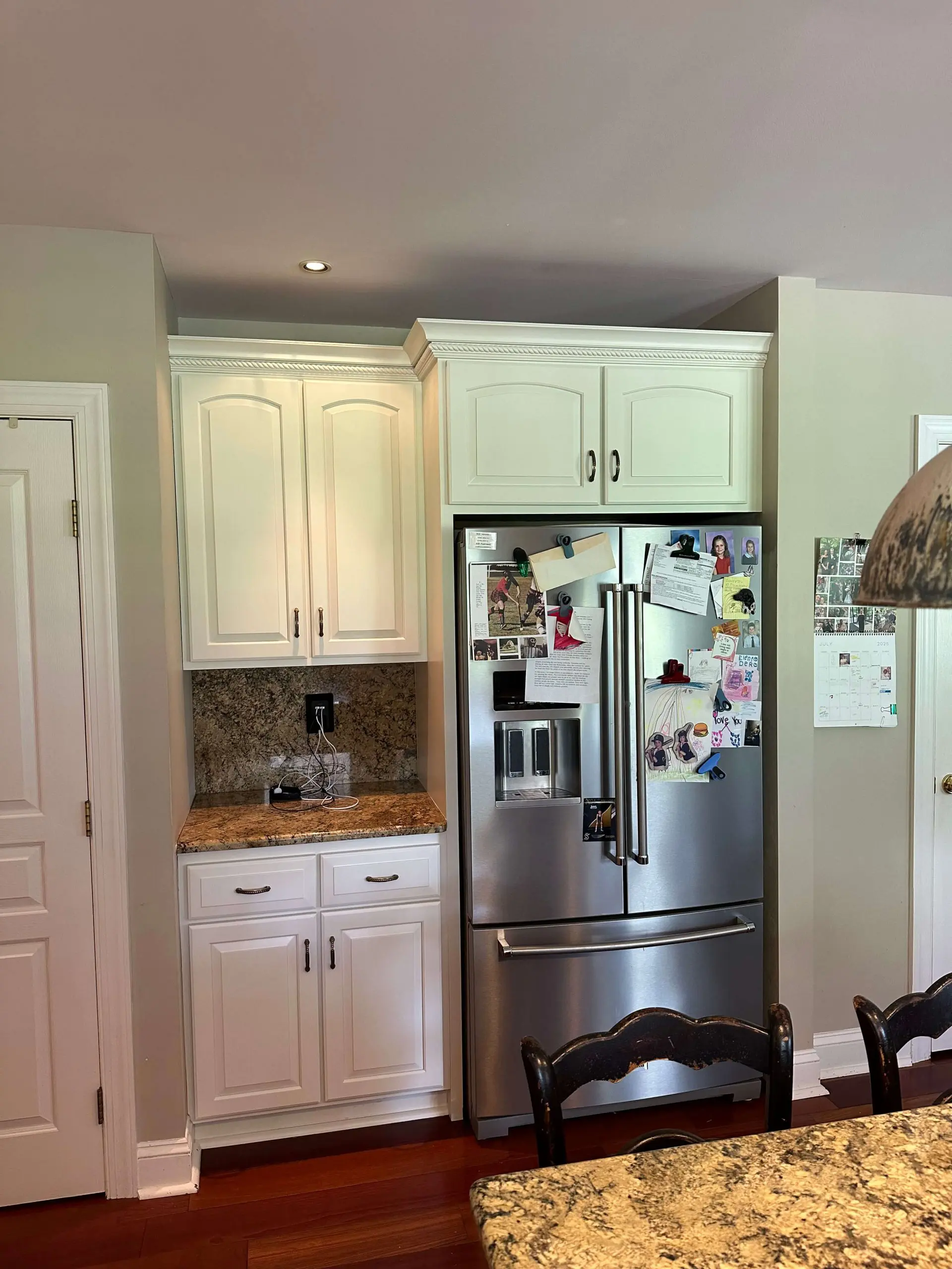 Modern kitchen featuring white cabinetry and granite countertops by Martzall's Custom Surfaces surrounding a stainless steel French door refrigerator.