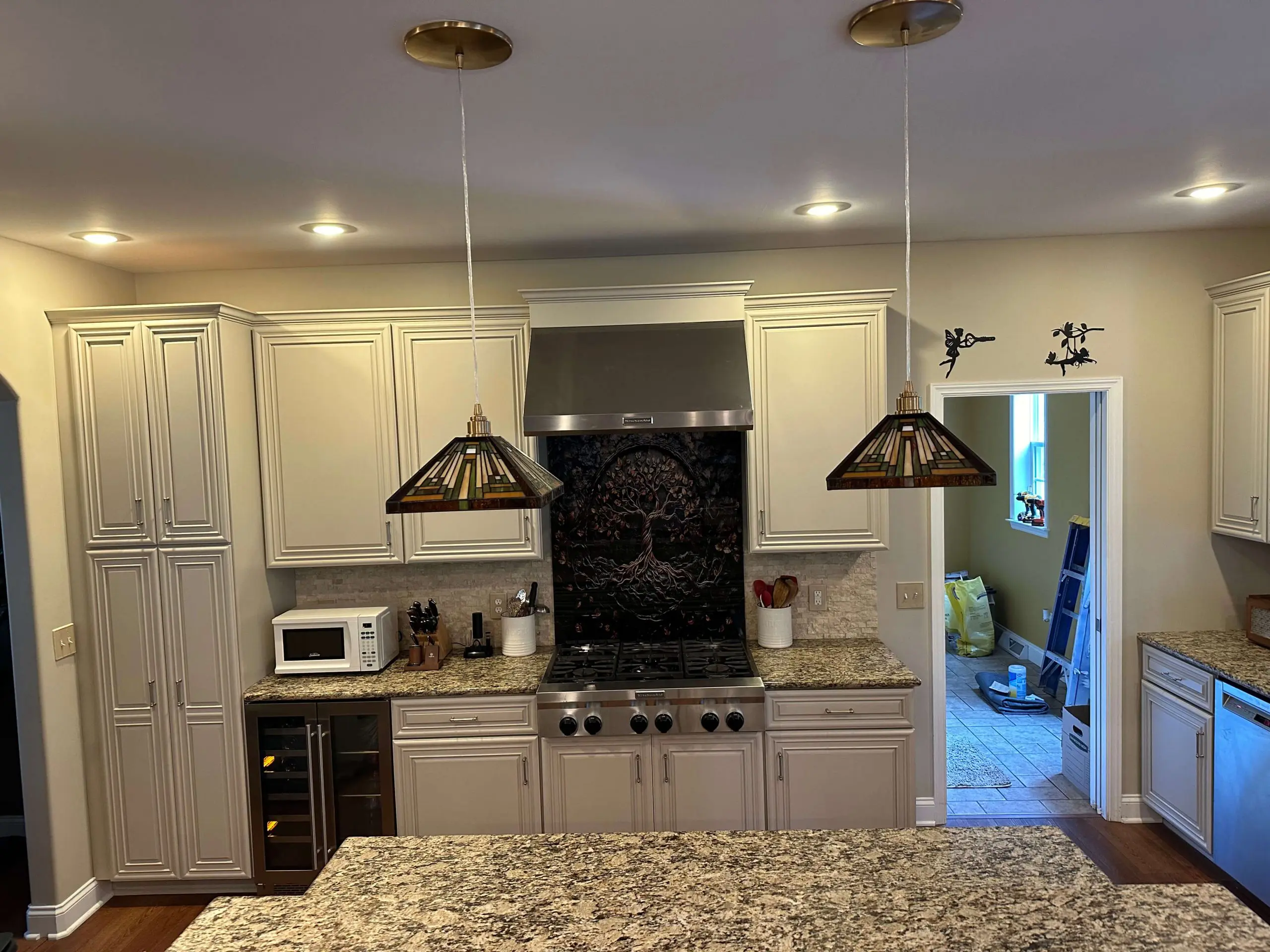 Modern kitchen featuring a granite island, custom tile backsplash, and designer pendant lighting installed by Martzall's Custom Surfaces.