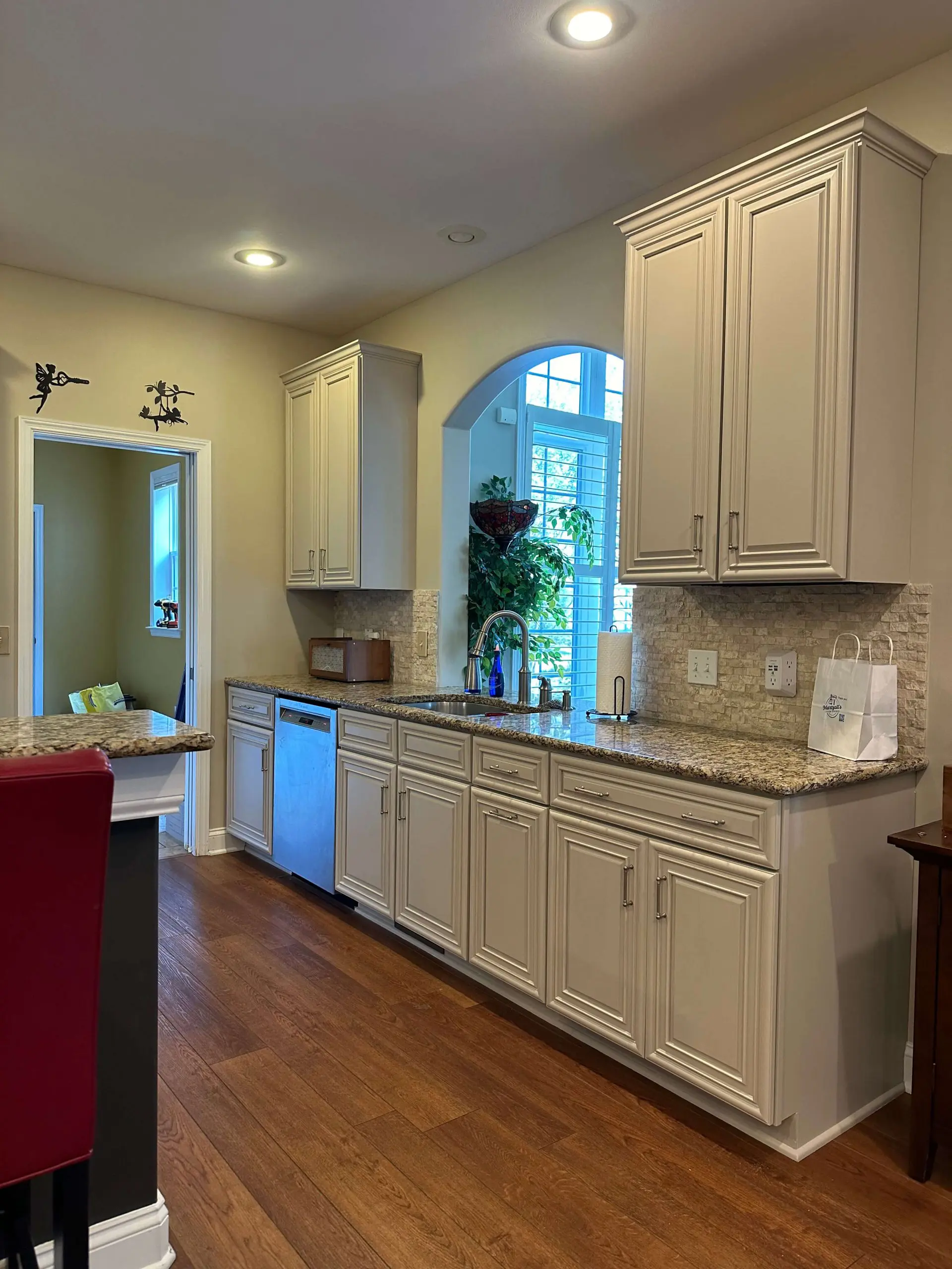 Elegant off-white kitchen cabinetry with granite countertops and stone tile backsplash handcrafted by Martzall's Custom Surfaces.