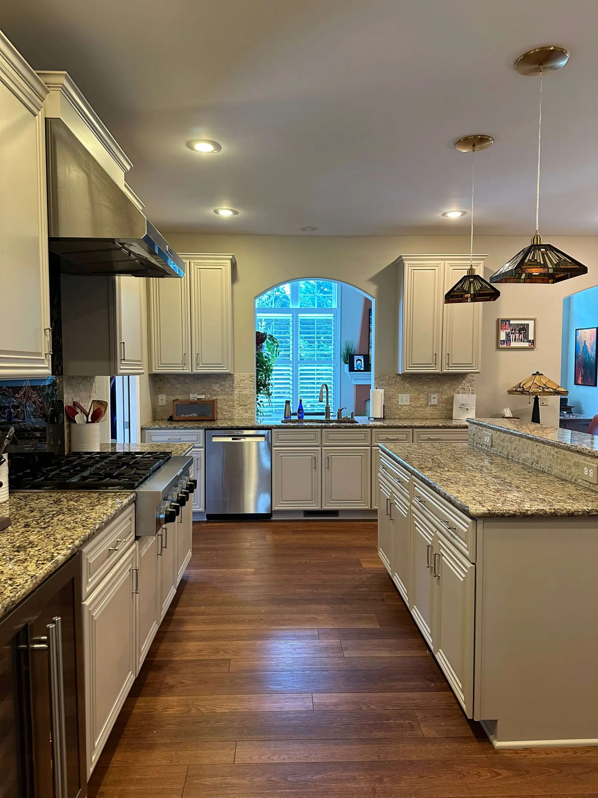Elegant kitchen remodel by Martzall's Custom Surfaces featuring earth-toned granite countertops, a tiered island, and classic cream cabinetry.