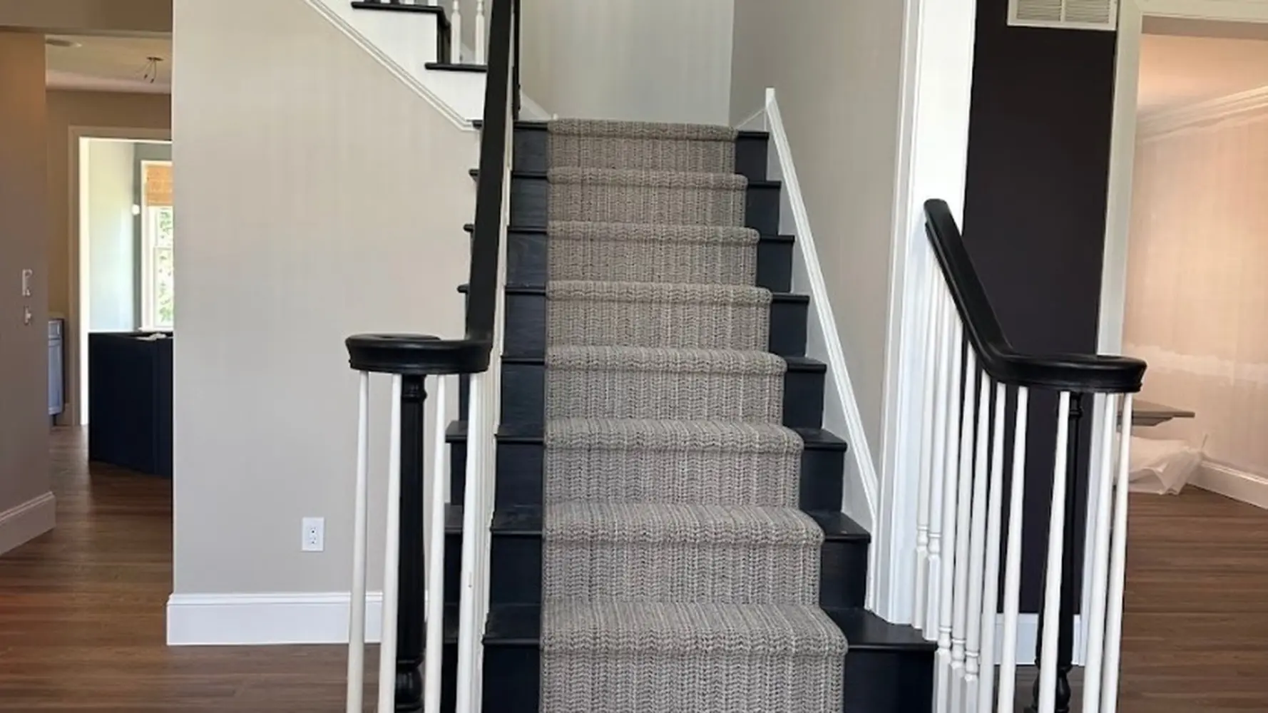 Professionally painted staircase and hallway with taupe walls, white trim, and black railings by Martzall's Custom Surfaces in Lancaster County, PA