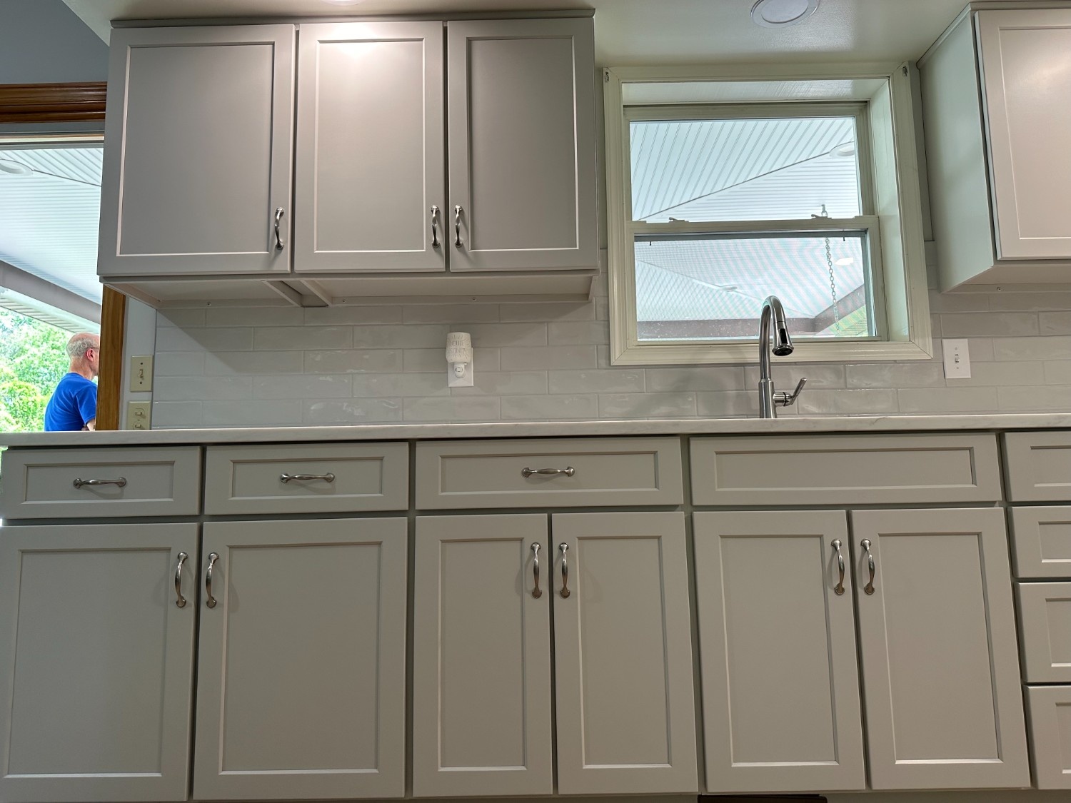Modern kitchen featuring light grey shaker-style cabinets and a light grey subway tile backsplash professionally installed by Martzall's Custom Surfaces.
