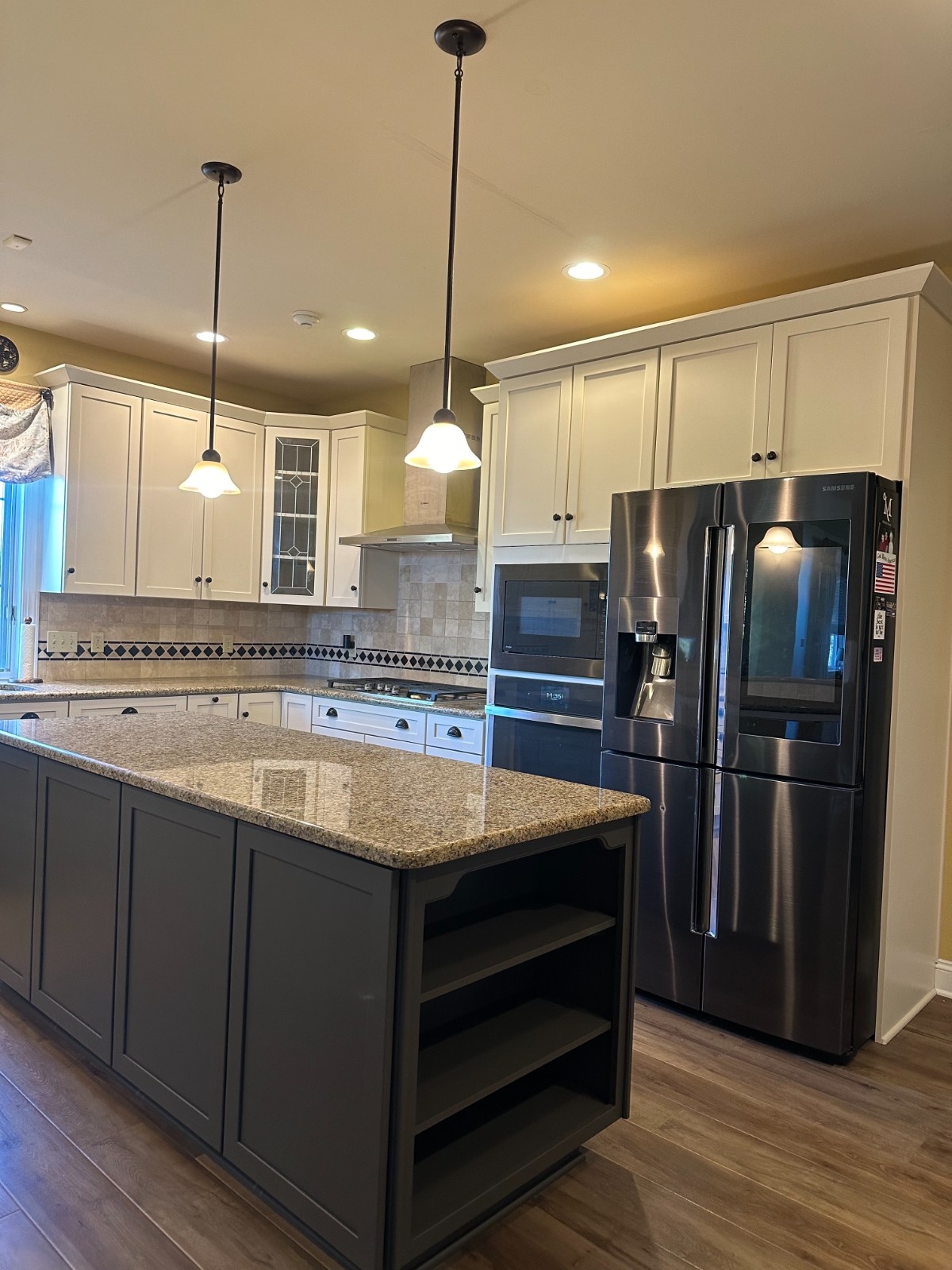 Classic kitchen remodel featuring Martzall's Custom Surfaces polished granite countertops paired with a dark grey island, white cabinetry, and earth-toned backsplash.