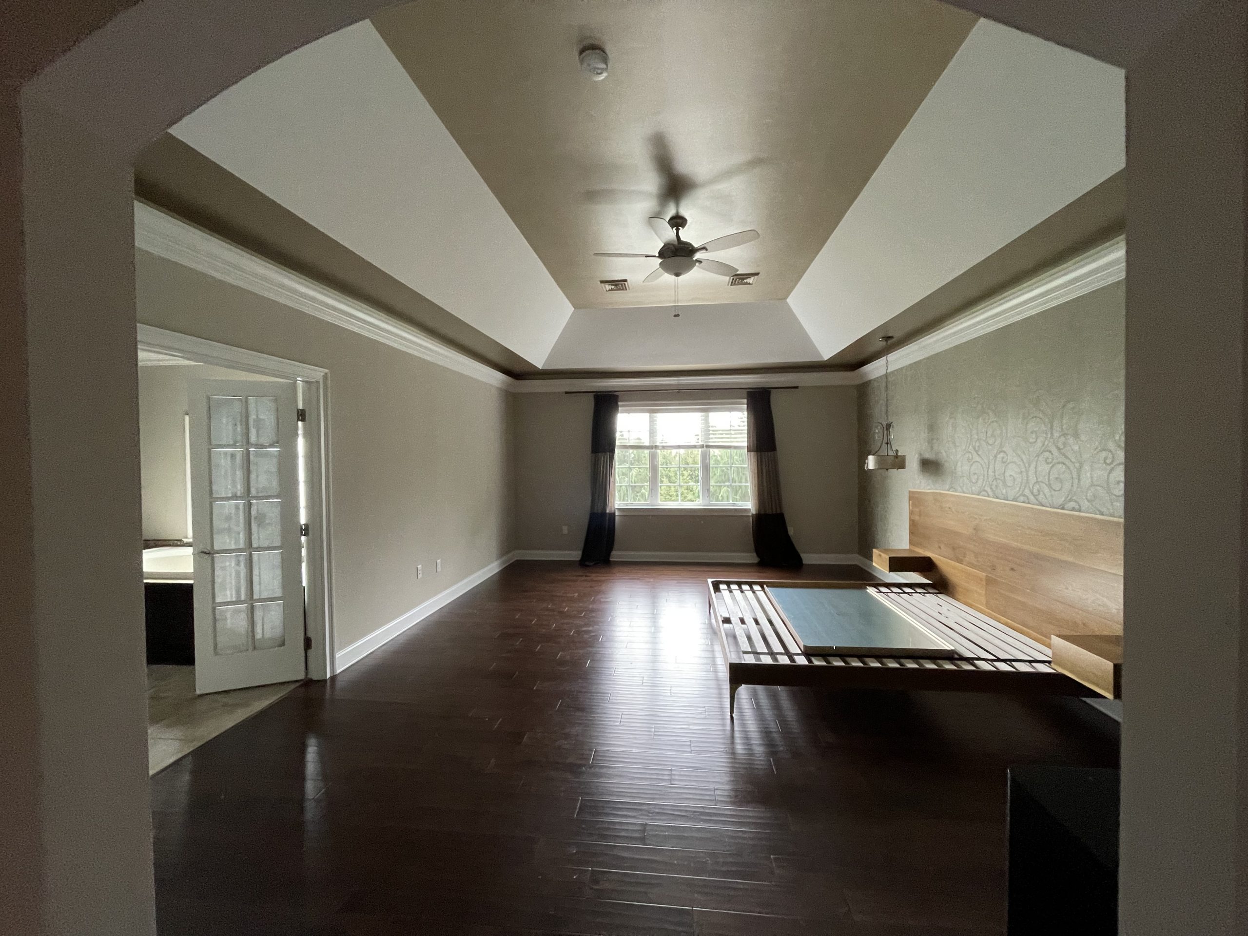 Elegant primary bedroom featuring a tray ceiling, crown molding, and hardwood floors expertly finished by professional painters in Leola, PA.