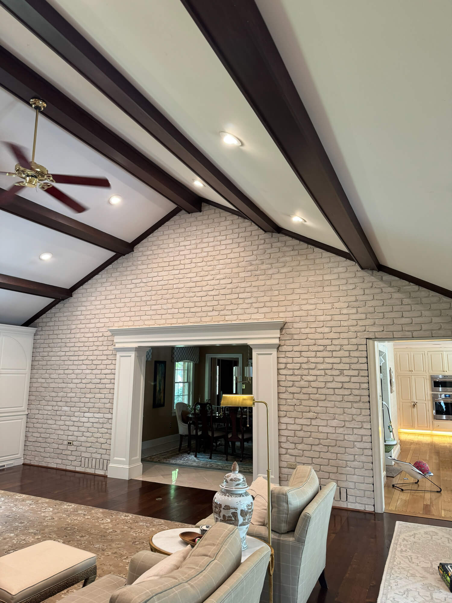 Interior living space with painted white brick accent wall and dark wood ceiling beams completed by Martzall’s Custom Surfaces serving Lititz, PA and surrounding Lancaster County communities