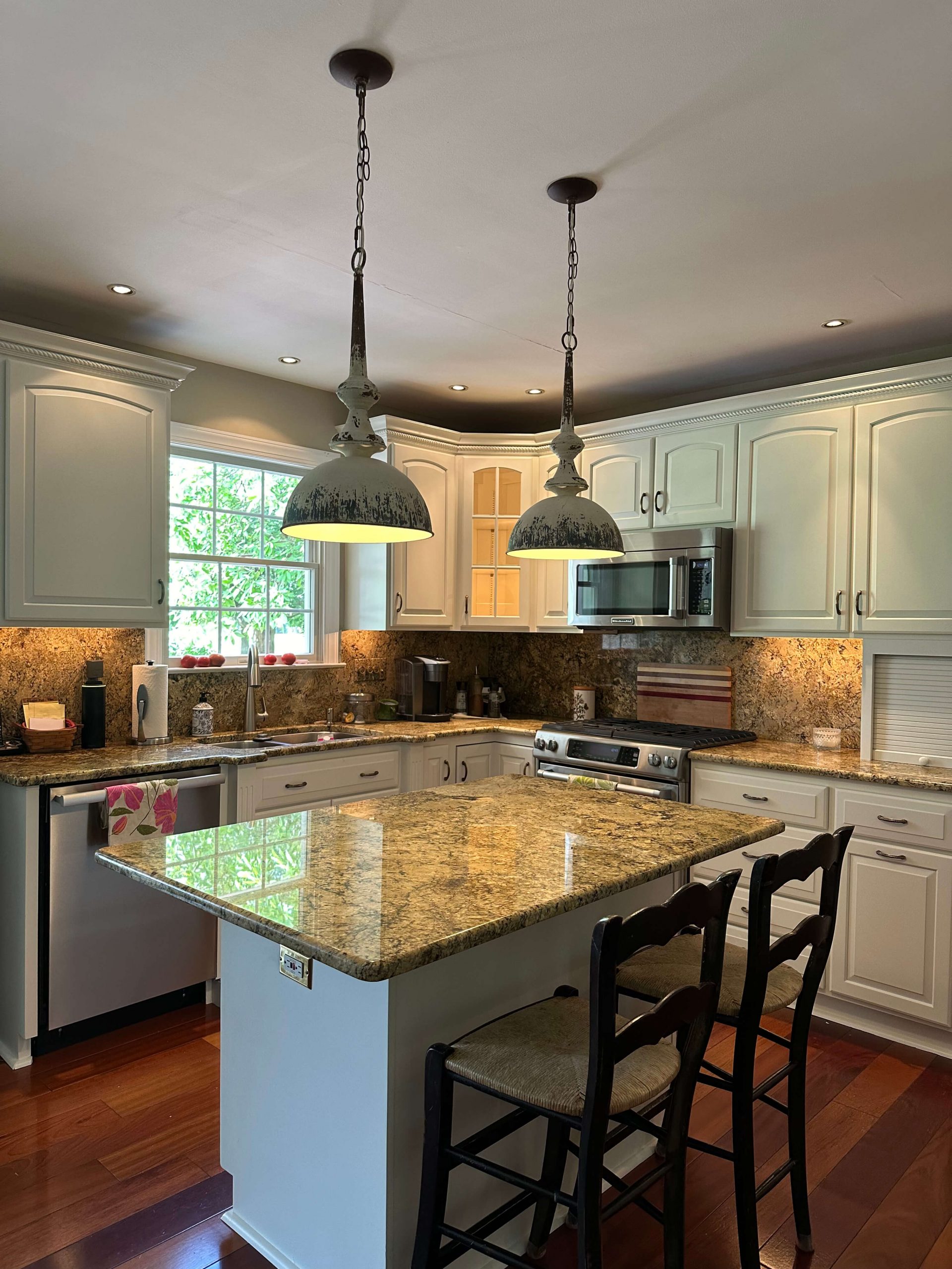Kitchen featuring Martzall's Custom Surfaces granite countertops, white cabinetry, rustic pendant lighting, and hardwood flooring.